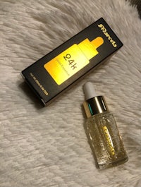 a gold bottle with a box next to it