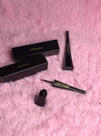 a set of black eyeliner and mascara on a pink fur