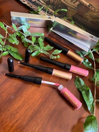 four lipsticks on a table next to a plant