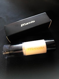 a bottle of concealer and a box on a table