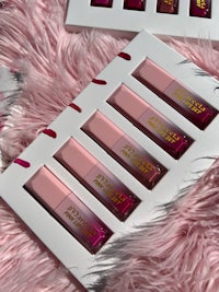 four lipsticks in a pink box on a furry surface
