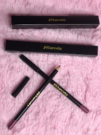 a black pencil and a pink pencil on top of a pink fur