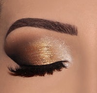 a close up of a woman's eye with gold and silver makeup