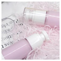 two bottles of pink liquid cosmetics sitting on top of a piece of paper