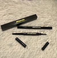 two black brow pencils on a furry surface