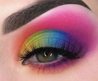 a close up of a woman's eye with a rainbow colored eyeshadow